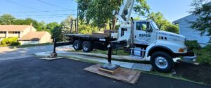 A piece of Aspen Tree equipment using protective mats to avoid doing any damage to a yard and driveway in Clifton, NJ.