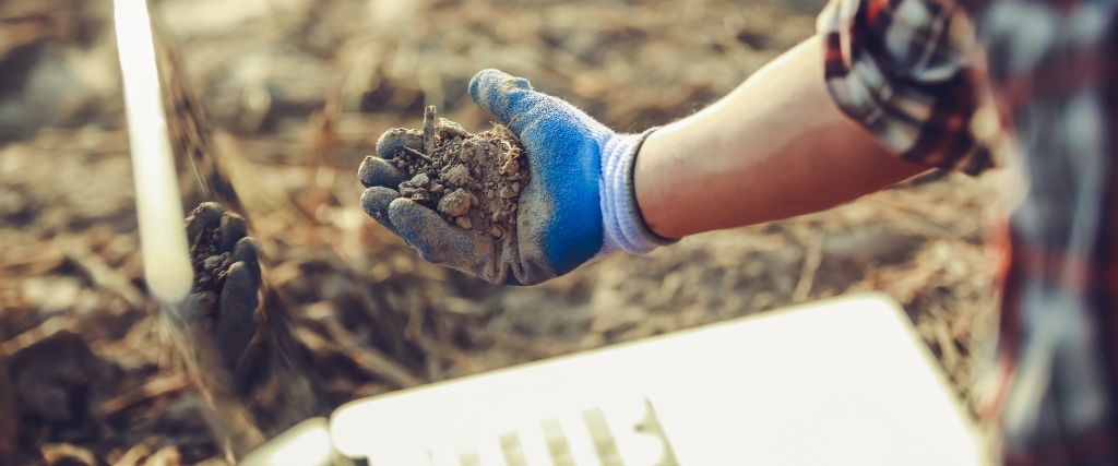 A man holding a handful of light brown soil as he checks for soil compaction in a Hasbrouck Heights, NJ neighborhood.