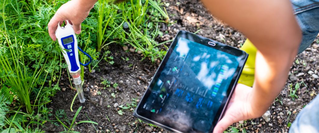 Woman using a soil pH tester to evaluate the soil in her garden.